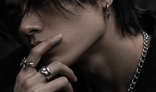 Silver-tone jewelry worn in a dark, close-up portrait