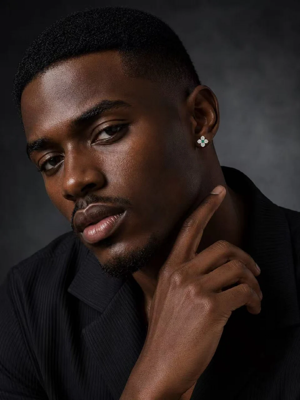 Close-up portrait with a flower-shaped stud earring and a hand resting at the neck